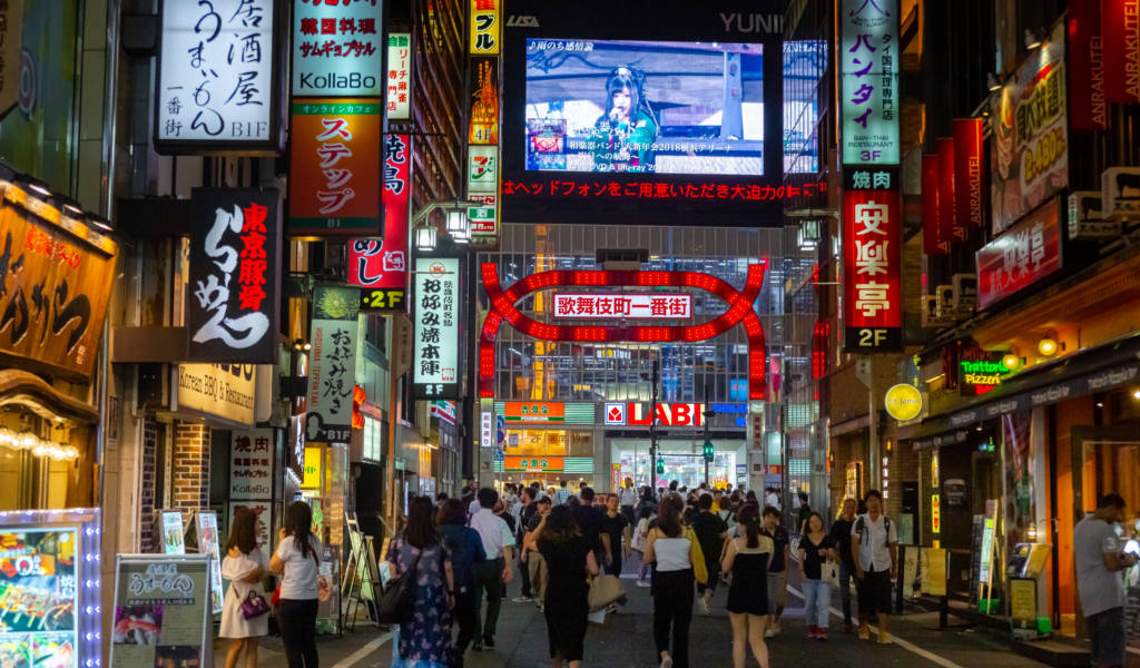 A Tokyo Xplorers guide leading a small group through a neon-lit Shinjuku alley at night
